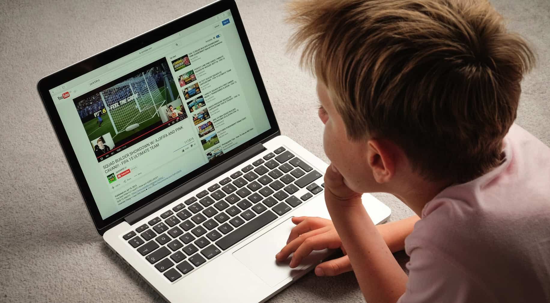ребенок смотрит видео на YouTube с ноутбуком